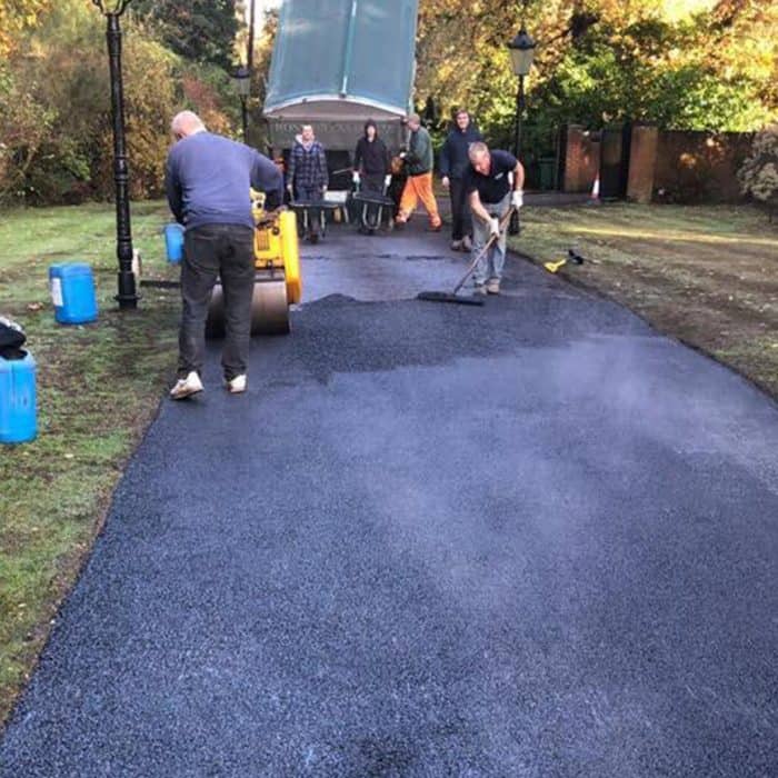 A group of builders are working on a paved road.