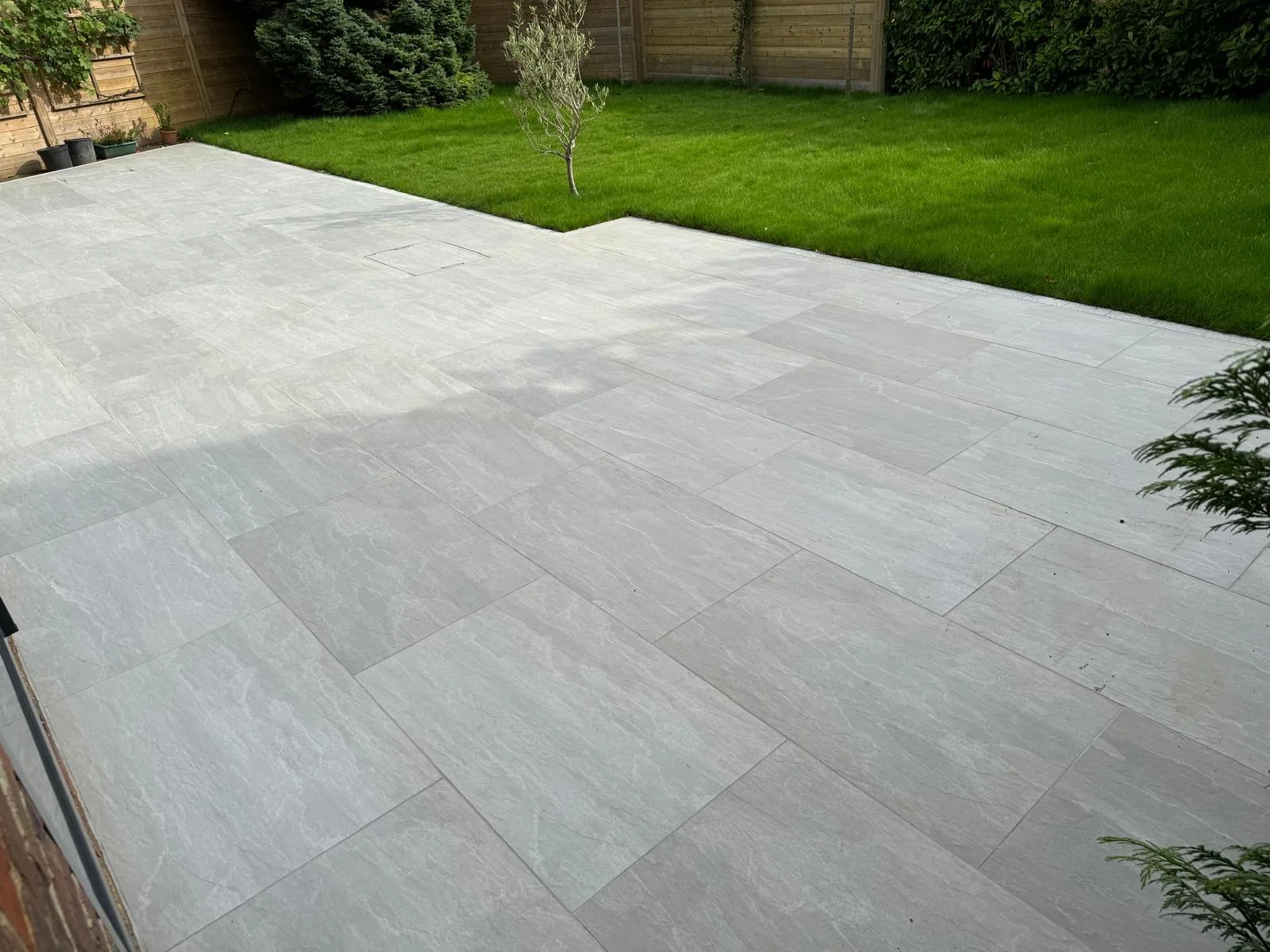 Large completed porcelain patio beside a landscaped Surrey garden