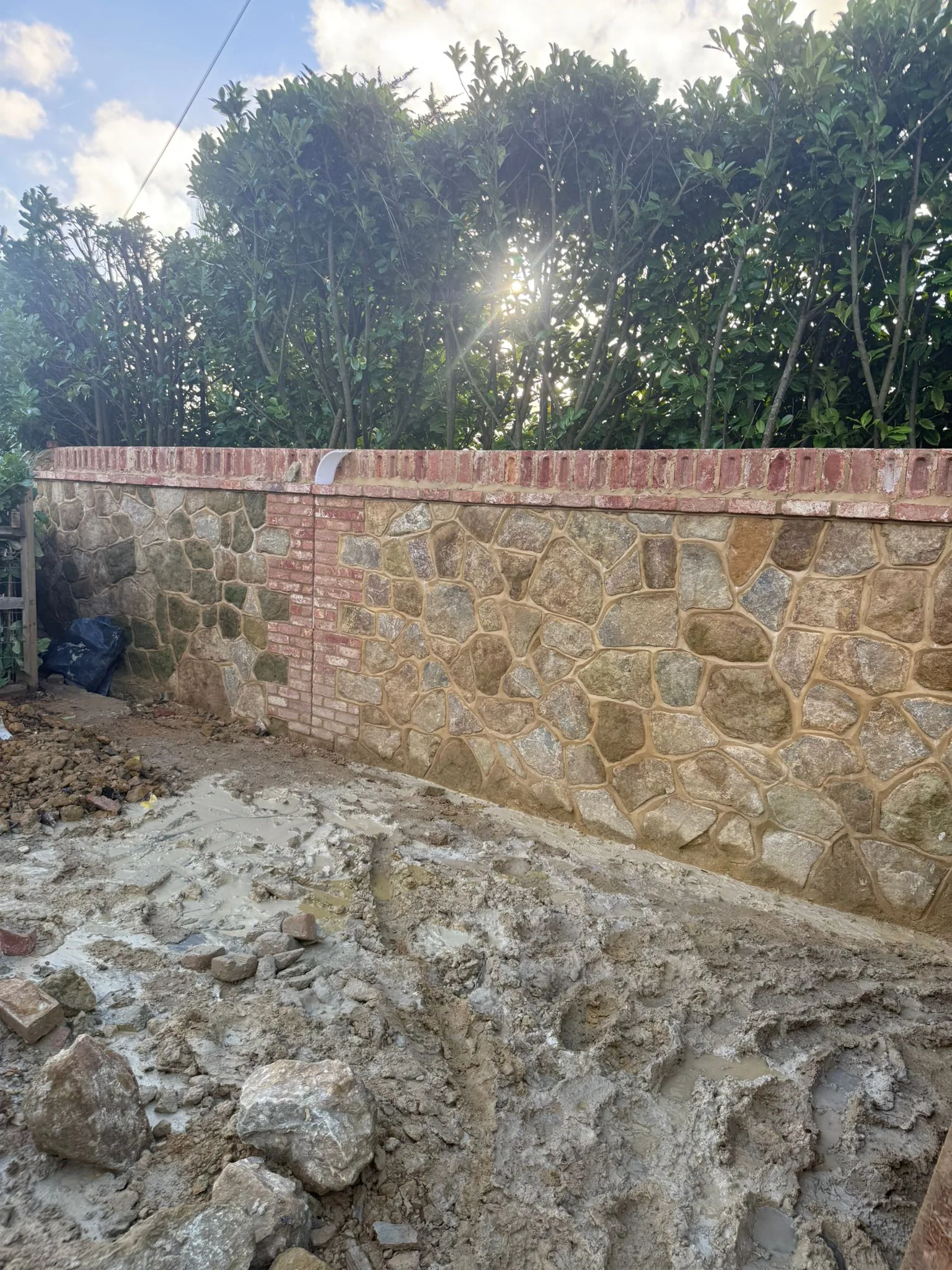 Natural stone boundary wall with brick piers reconstructed in Surrey